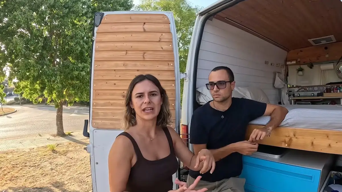 Sara y Tony en las puertas traseras de su furgoneta camper explicando el almacenamiento y la cama