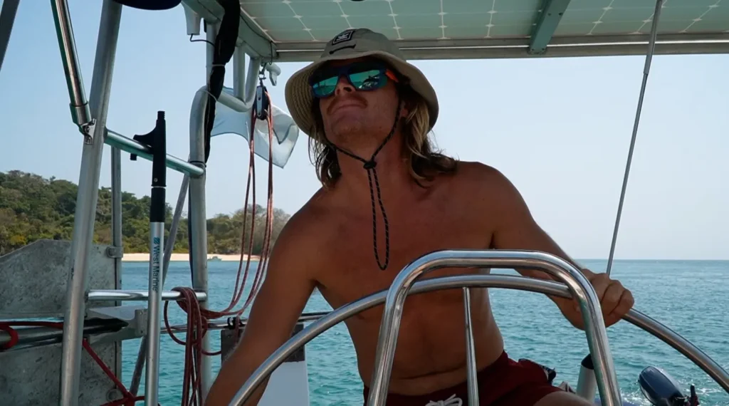 Navegante al mando del timón de un velero en aguas tropicales durante una travesía oceánica.
