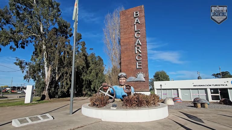 Portal de acceso a la ciudad de Balcarce con tótem informativo y escultura homenaje a Juan Manuel Fangio al volante.