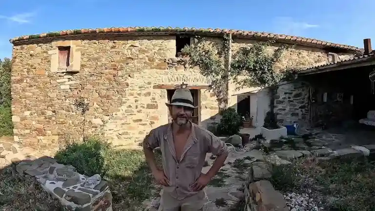 Arnau de pie frente a masía tradicional de piedra en Cataluña