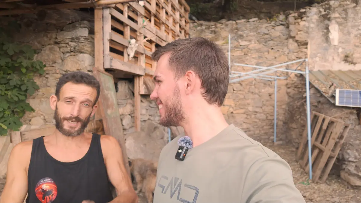 Arnau Serrado conversando y riendo junto a Bernat frente a la cabaña reciclada durante su visita en la montaña.