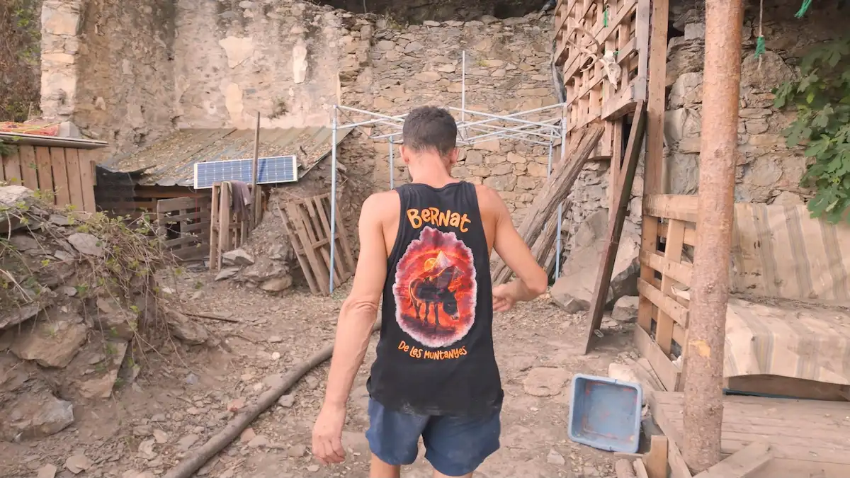 Bernat recorriendo el sector de su cabaña con paneles solares y maderas recicladas para su vida autosuficiente en la montaña.