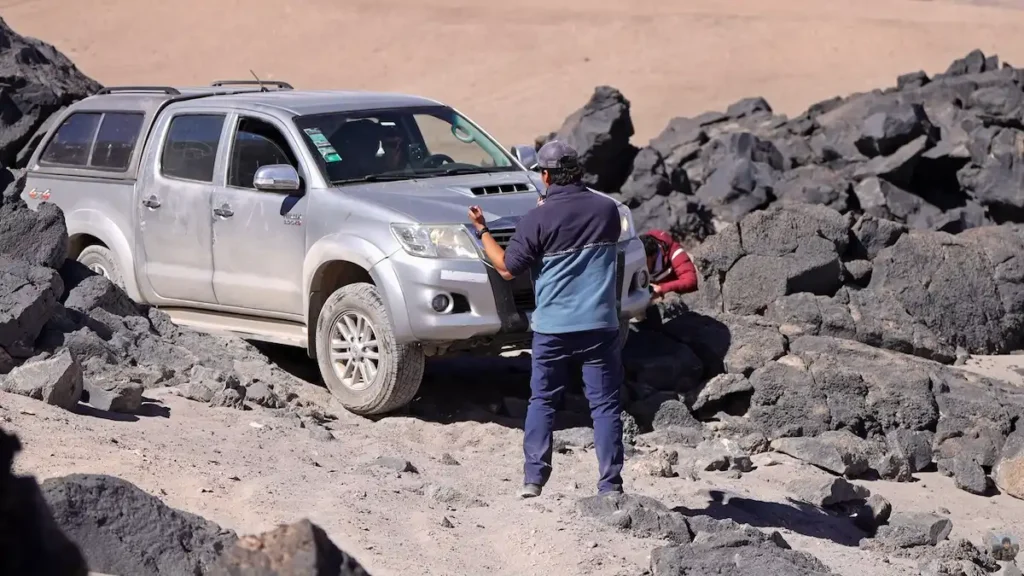 Camioneta 4x4 realizando maniobras de off-road extremo y trepando sobre grandes piedras en un camino de montaña empinado en Catamarca.