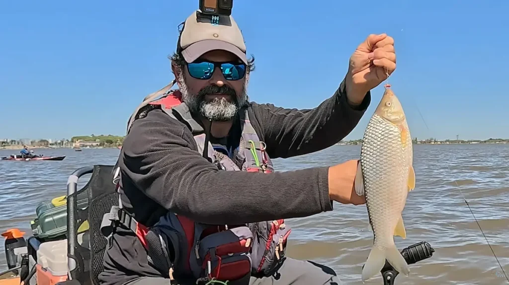 Pescador levantando una boga con la línea desde un kayak equipado en el Río de la Plata frente a Quilmes