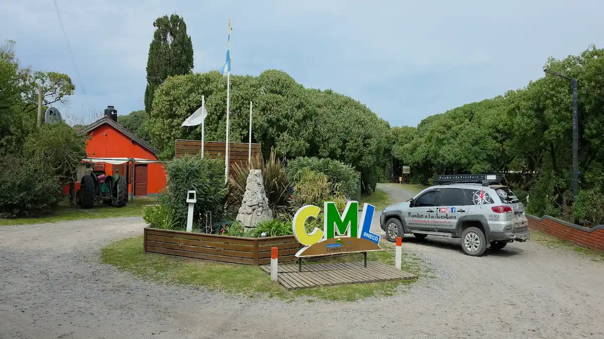 Vehículo de Rumbo A La Aventura frente al cartel de bienvenida del Complejo Camping Miguel Lillo en Necochea