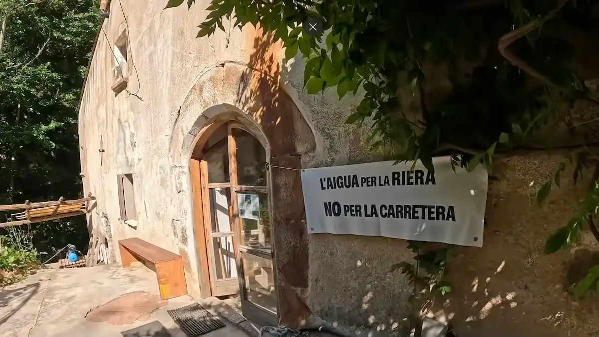 Fachada de la masía con cartel reivindicativo a la entrada de la eco-comunidad