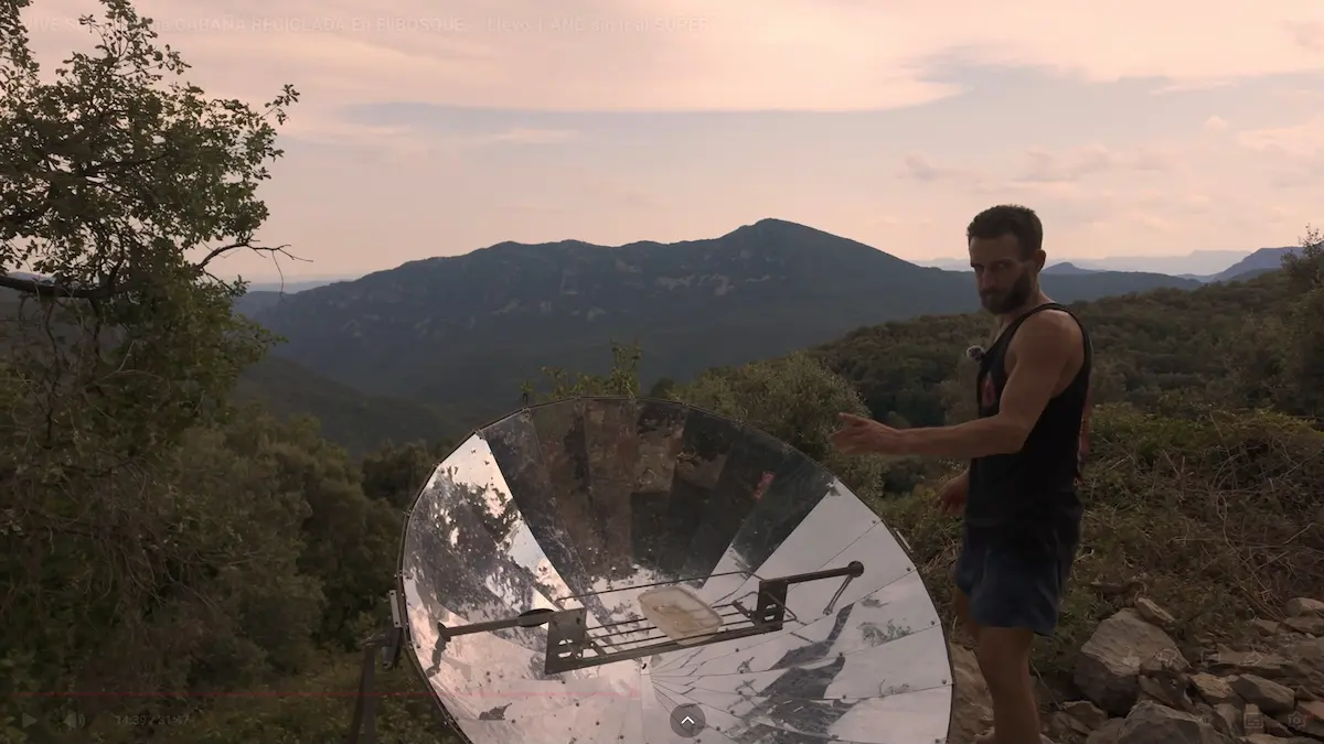 Bernat de les Muntanyes mostrando el funcionamiento de su cocina solar parabólica como parte de su vida autosuficiente en el bosque.