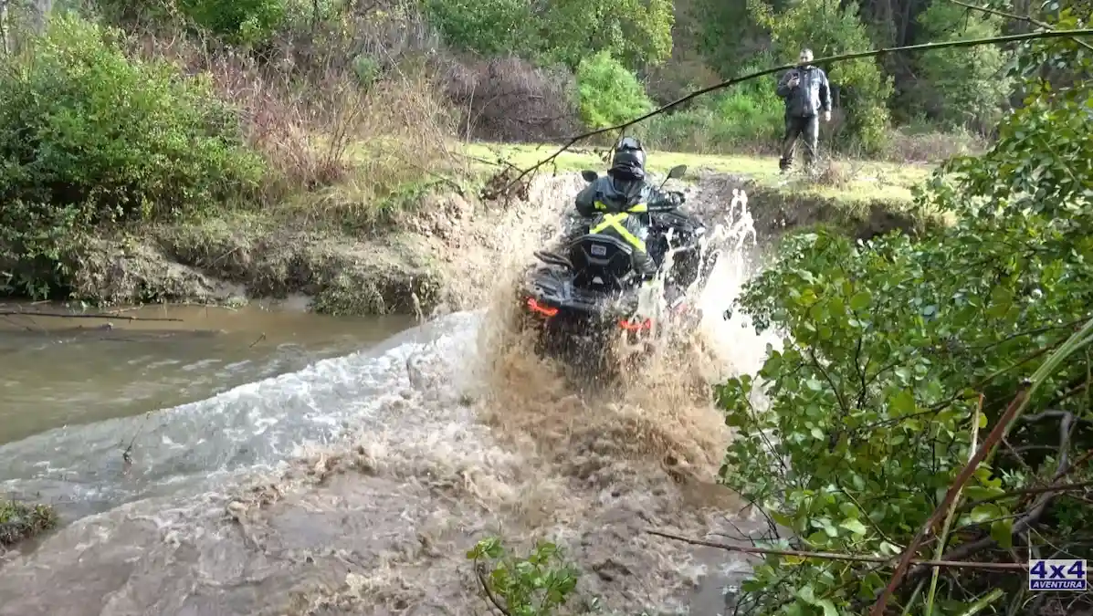 Cuatriciclo ATV cruzando a toda velocidad un río con gran salpicadura de agua en Chile.
