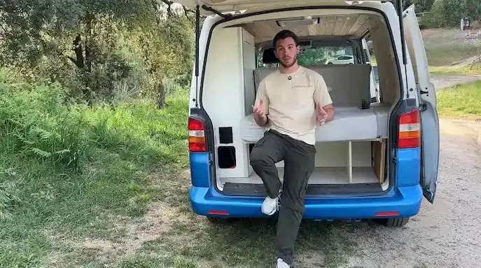 Arnau Serradó, creador de contenido y nuevo embajador de la Red Rumbo, posando junto a su furgoneta camperizada.