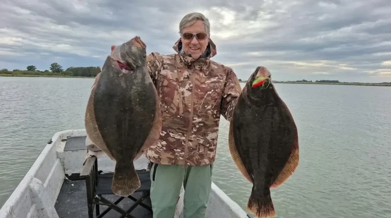 El pescador Jorge posa a bordo mostrando dos grandes lenguados capturados en simultáneo en la albufera de Mar Chiquita.