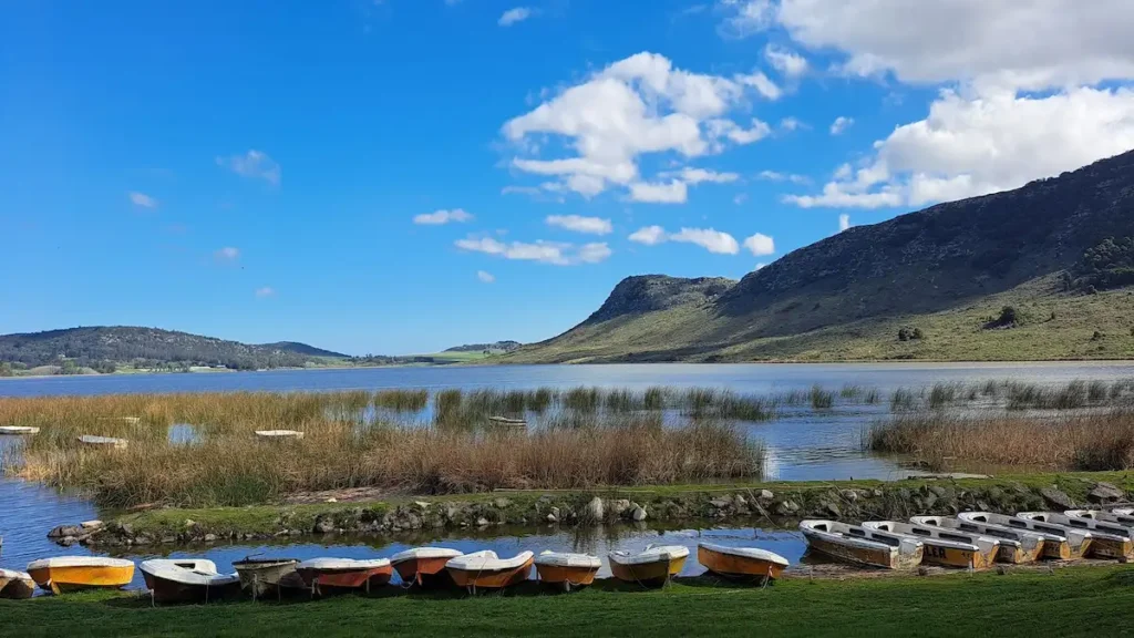 Botes de alquiler amarrados en la costa frente a los juncales y las sierras en el Club de Pesca Balcarce de Laguna La Brava