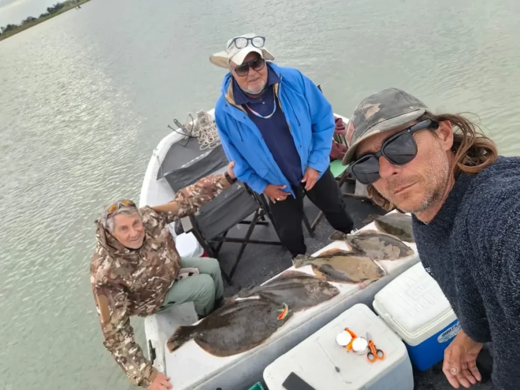 Martín Díaz Vignola junto a Ricardo y Jorge, sonriendo a bordo de una embarcación durante una jornada de pesca.