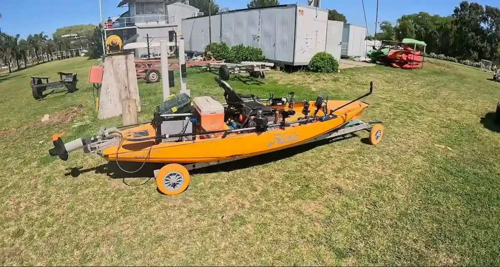 Kayak Hobie naranja totalmente equipado con motor y accesorios sobre un carrito tipo cuna en el predio del Club Náutico Quilmes
