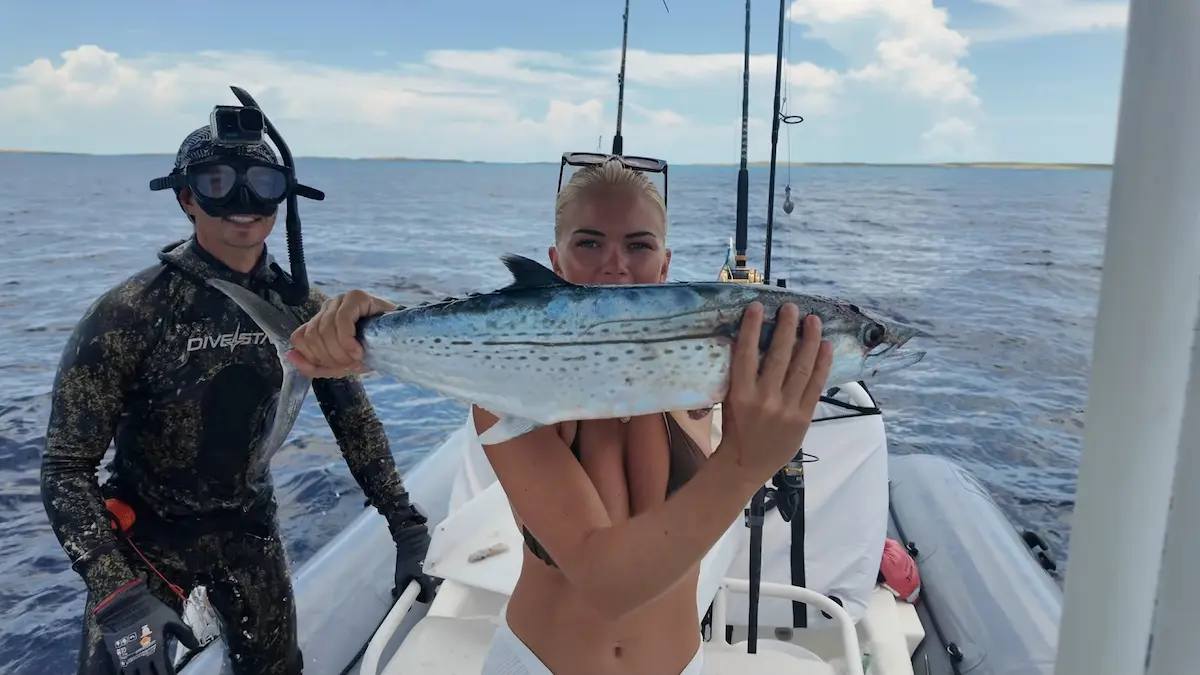 Pescadora exhibiendo una sierra recién capturada a bordo del bote auxiliar junto al buzo en Bahamas.