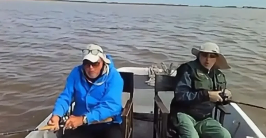 Dos pescadores navegando a bordo de un bote durante una jornada de pesca embarcada con cañas y reeles rotativos.