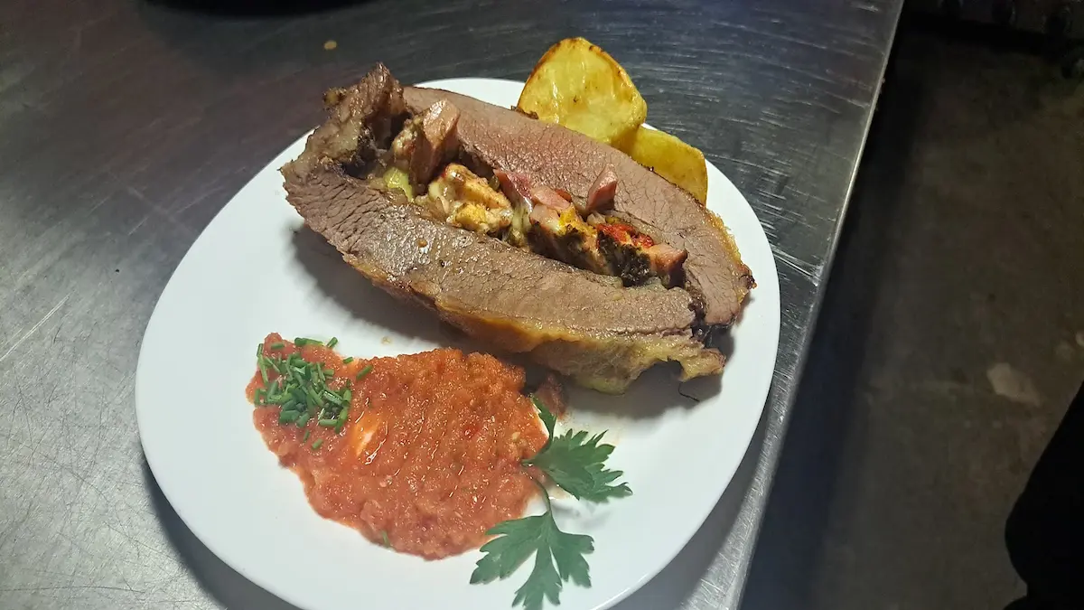Plato de carne rellena con papas rústicas y salsa criolla en el restaurante del Camping Miguel Lillo en Necochea.