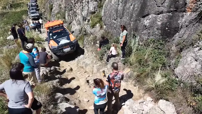 Caravana de camionetas de Sin Huellas 4x4 avanzando por una huella técnica de piedras con guías y espectadores en la travesía Minas Fantasma.
