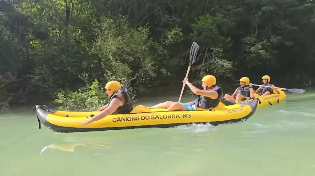 Grupo de viajeros con cascos amarillos navegando en kayak inflables por el río de los Cânions do Salobra (Mato Grosso do Sul) en una travesía de Sin Huellas 4x4