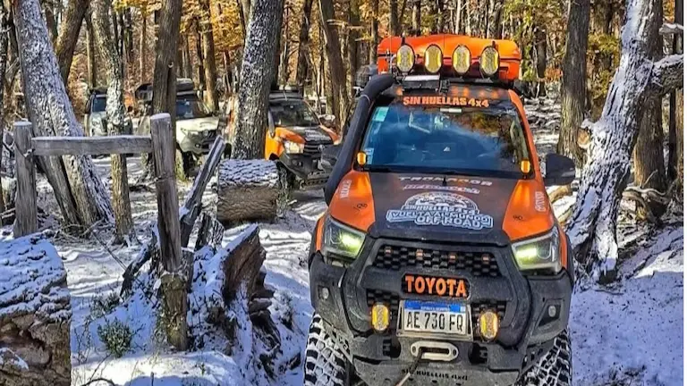 Toyota Hilux de Sin Huellas 4x4 equipada para expedición off-road avanzando entre la nieve y el bosque patagónico hacia el Paso Río Mayer.