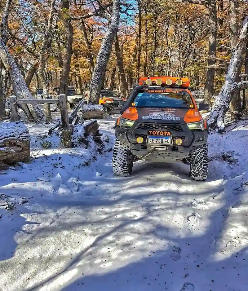 Camioneta Toyota Hilux equipada para travesía off-road transitando una huella con nieve y árboles en la Patagonia con Sin Huellas 4x4.