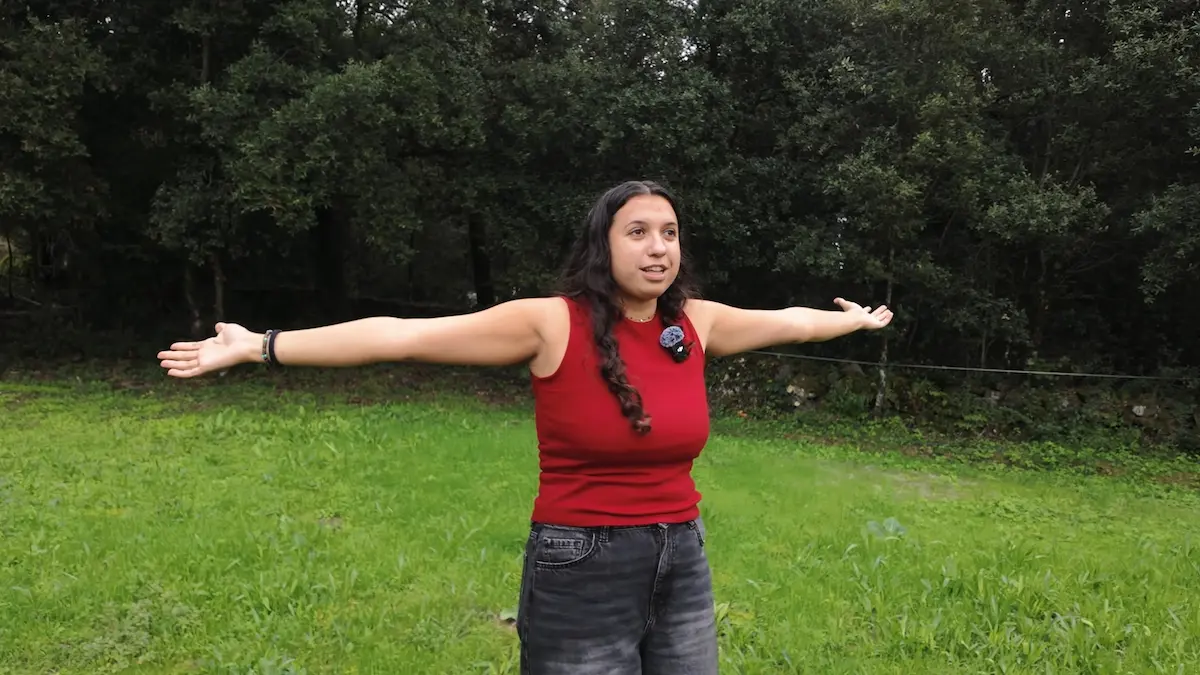 Estrella Burruezo con los brazos abiertos en medio del campo verde mostrando las dimensiones de su finca.